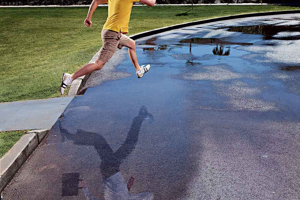 Young man jumping over puddle reflection turns him inot business hero